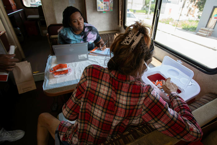 LaShonda Jefferson (left), a community health educator, talks with a woman who drops off used needles into a bin on the van.