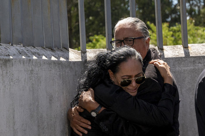 Lorena Villavicencio, sister of slain presidential candidate Fernando Villavicencio, embraces her husband outside the morgue where her brother's body is being held, in Quito, Ecuador, Thursday, Aug. 10, 2023.