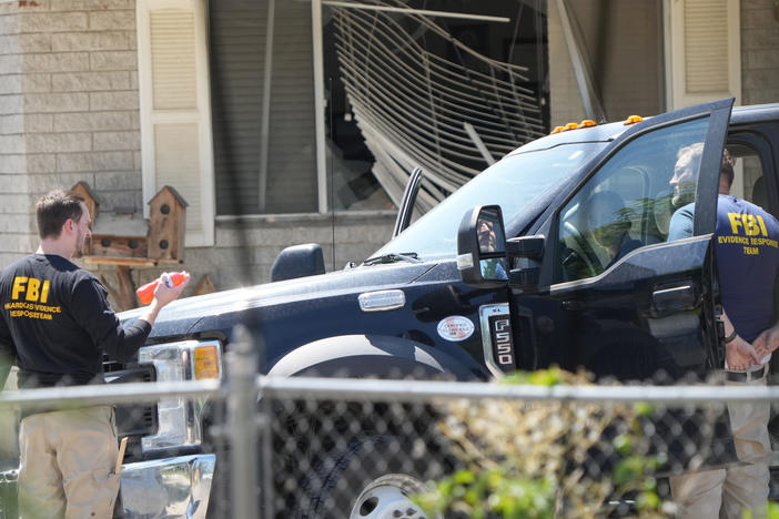 FBI agents process the home of Craig Robertson who was shot and killed by the FBI in a raid on his home on Wednesday in Provo, Utah. The FBI was investigating alleged threats by Robertson to President Biden ahead of the president's visit to the state this week.