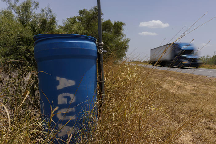 A water station for immigrants containing sealed jugs of fresh water sits along a fence line near a roadway in rural Jim Hogg County, Texas, on July 25.