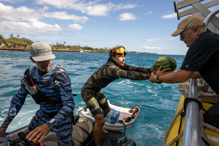 John Picard hands a watermelon to Ridge Lenny as part of the donated items he and other members of the local surfing community are helping transport to Lahaina residents in need.