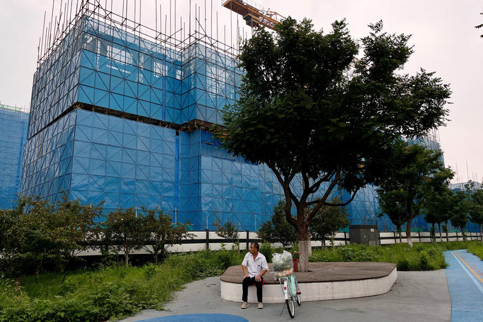 A person sits near a construction site of residential buildings by Chinese developer Country Garden, in Beijing, Aug. 11. Country Garden is facing major financial challenges.