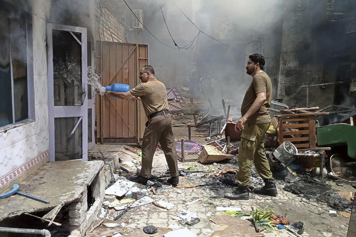 In this photo provided by district police office, a police officer pours water into a burning house in a Christian neighborhood in Jaranwala, near Faisalabad, Pakistan, Wednesday. A mob burned a church and damaged at least four others, police and local Christians said. The mob also demolished a man's house after accusing him of desecrating Islam's holy book, and attacked other Christian homes.