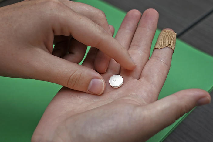 A patient prepares to take mifepristone, for a medication abortion. A federal appeals court ruled to impose new restrictions on the drug Wednesday but the ruling will not take effect until the Supreme Court weighs in.