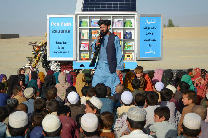 Matiullah Wesa, cofounder of the education charity PenPath in Afghanistan, speaks to children during a class next to his mobile library in a district of Kandahar Province. Wesa and his brother were among the Afghan men who have called for the Taliban to reverse its bans on higher education for girls. He was arrested in March and has been held in prison since then with no formal charges.