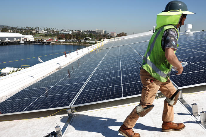 Workers install solar panels on a rooftop at AltaSea's research and development facility at the Port of Los Angeles on April 21, 2023.