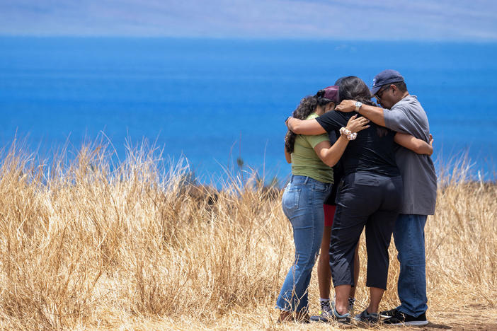 Volunteers helping those who lost homes in Lahaina stop to pray on a hillside. The town is surrounded by dry, invasive grasses which are highly flammable.