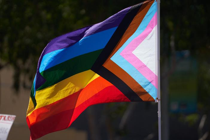 A business owner was fatally shot Friday after someone allegedly took issue with a Pride flag she had displayed at her clothing store in Cedar Glen, Calif. Here, a Progress Pride Flag is held above a crowd of LGBTQ+ activists in West Hollywood, Calif., in April 2023.