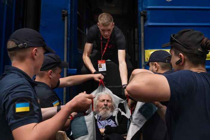 Eduard Skoryk (center) helps lift Viktor Nesterov onto an evacuation train.