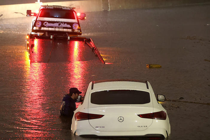 A tow truck driver attempts to pull a stranded car out of floodwaters on the Golden State Freeway as tropical storm Hilary moves through the area on August 20, 2023 in Sun Valley, California.
