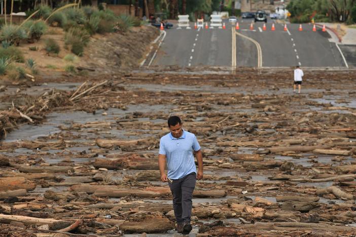 A worker from the Coachella Valley Water Department surveys debris flowing across a road following heavy rains from Tropical Storm Hilary, in Rancho Mirage, Calif., on Monday.