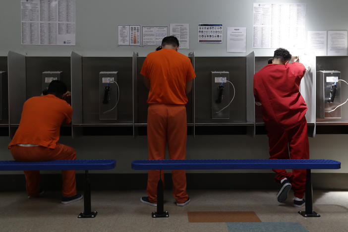 Immigrants in the custody of U.S. Immigration and Customs Enforcement (ICE) use the phones at a detention center in California in 2019. Secret government reports obtained by NPR described "negligent," "barbaric" and "filthy" conditions in ICE detention.