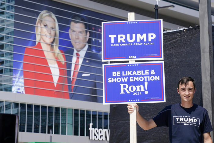 A former President Donald Trump supporter stands near the Fiserv Forum Tuesday as setup continues for Wednesday's Republican presidential debate in Milwaukee.