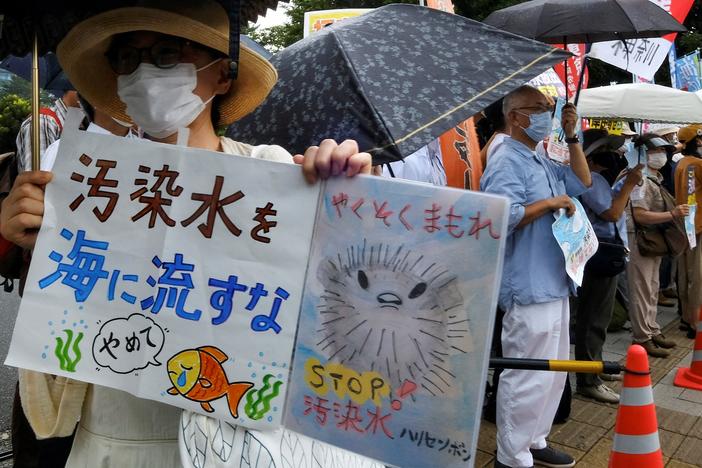 A protester, left, holds signs reading "Don't throw polluted water into the sea" and "keep your promise" as they take part in a rally against the Japanese government's plan to release treated wastewater from the crippled Fukushima Daiichi power plant into the ocean in Tokyo on August 22, 2023.