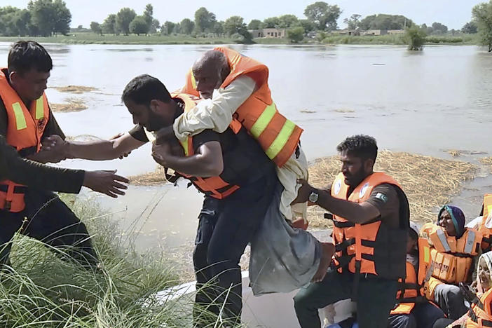 In this photo released by Rescue 1122 Emergency Department, rescue workers help a villager as he and others are being evacuate from a flooded area of Bahawalnagar district in Pakistan's Punjab province on Wednesday, Aug. 23, 2023.