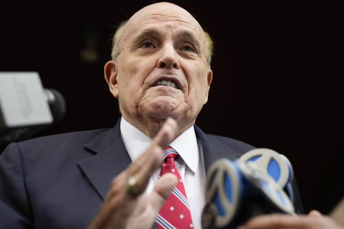 Rudy Giuliani speaks to reporters as he leaves his apartment building in New York on Wednesday to be booked in Atlanta.