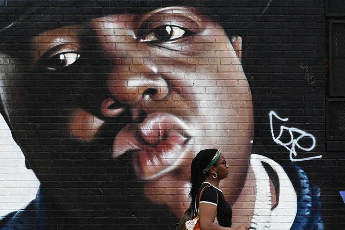 A woman passes by a mural of the rapper Biggie Smalls on a wall in the Bushwick section of Brooklyn.