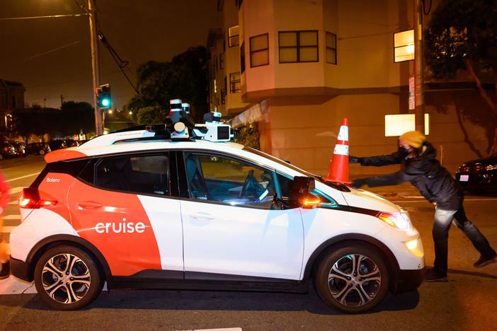 Members of Safe Street Rebel place a cone on a self-driving Cruise car in San Francisco.