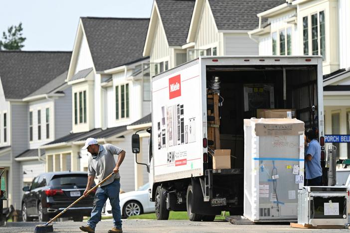 A maintenance worker sweeps the street in front of a row of new homes in Fairfax, Va., on Aug. 22. Sales of new homes are taking off as current homeowners are reluctant to sell their houses, because they would face a higher mortgage for their next one.