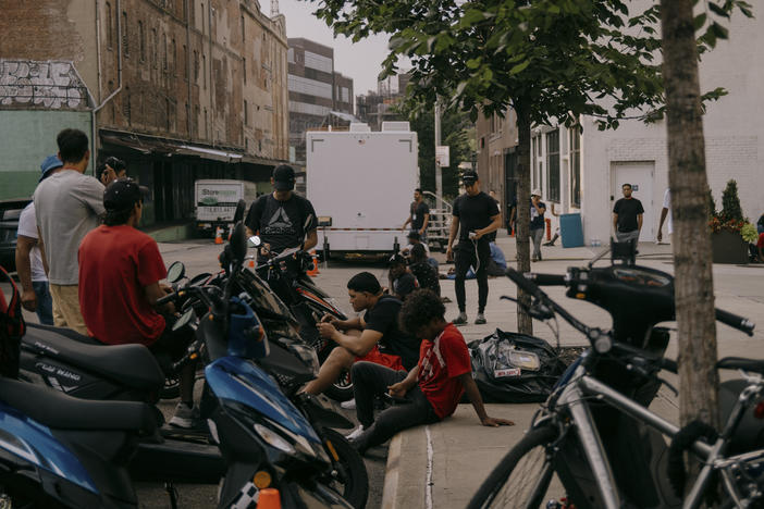 Migrants at the Clinton Hill Shelter seek relief from the overcrowded confinements of 47 Hall St. Residents working as delivery drivers wait for orders to come in on July 19 in Brooklyn, N.Y.