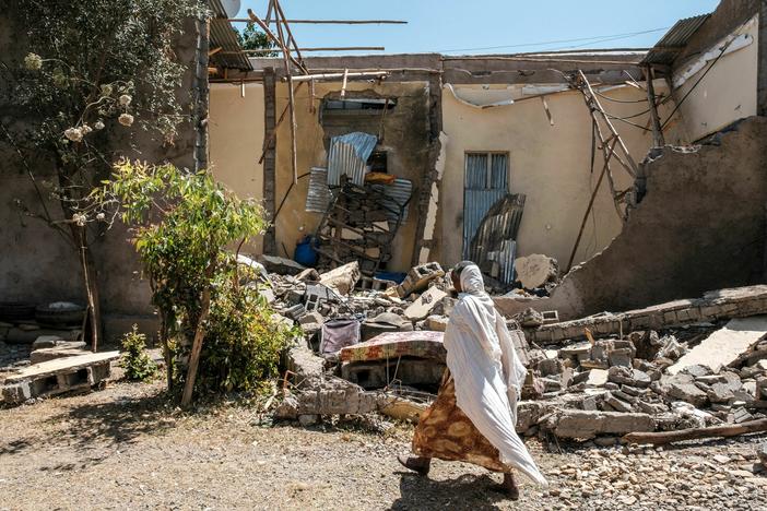 A woman walks in front of a house damaged by shelling in the city of Wukro, in Tigray, Ethiopia. A new report indicates that military forces have engaged in hundreds of sexual assaults on girls and women.