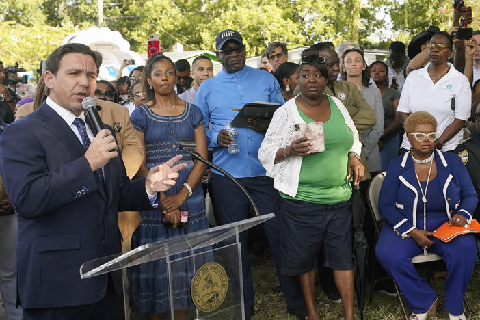Florida Gov. Ron DeSantis, left, speaks at a prayer vigil on Sunday for the victims of a mass shooting that took place Saturday in Jacksonville, Fla.