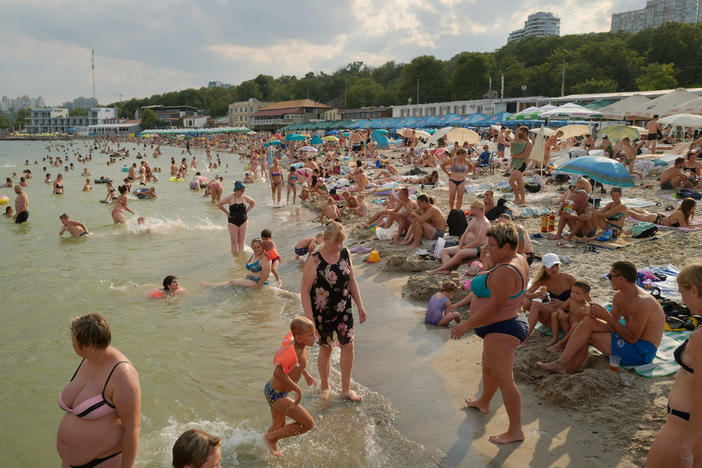 People swim and sunbathe on a reopened beach at the Black Sea on Aug. 22 in Odesa. When missiles and drone attacks first hit the city — and Russian naval vessels started laying explosive sea mines around the port — the beaches were closed. Warning signs urged people to keep their distance.