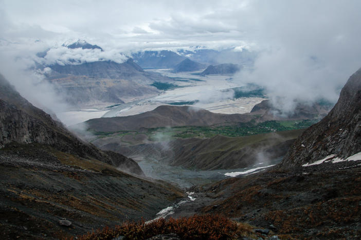 A view of the Pakistani territory of Baltistan from the heights of the mountain above the village of Chunda. The patches of white in the foreground are snow and water. The patches of silver in the distance are clouds that shroud the peaks of most mountains in Baltistan. The territory boasts towering peaks, including K2, the world's second highest mountain.