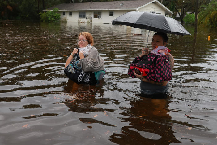 Makatla Ritchter and her mother, Keiphra Line, wade through flood waters after evacuating their home in Tarpon Springs, Florida. Flood waters from Hurricane Idalia inundated it on August 30, 2023. Climate change is making storm surge and intense rainfall during hurricanes like Idalia more dangerous.