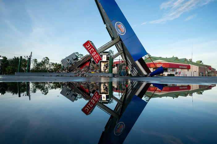 A storm-damaged gas station is reflected in a puddle in Perry, Fla., after Hurricane Idalia crossed the state on Wednesday.