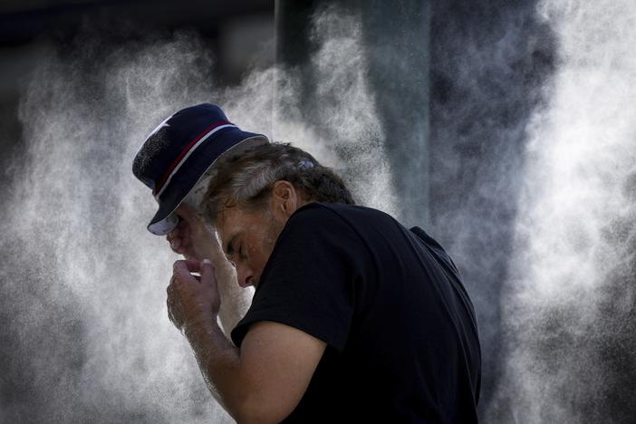A man cools off at a temporary misting station deployed by the city in the Downtown Eastside due to a heat wave, in Vancouver, British Columbia, Aug. 16, 2023.