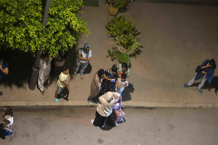 People take shelter and check for news on their mobile phones after an earthquake in Rabat, Morocco, late Friday, Sept. 8, 2023.