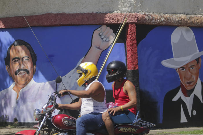 A motorcyclist rides past a mural of Nicaraguan President Daniel Ortega, left, and revolutionary hero CÃ©sar Augusto Sandino<em> </em>during general elections in Managua, Nov. 7, 2021. Ortega won a fourth consecutive term against a field of little-known candidates while those who could have given him a real challenge sat in jail.