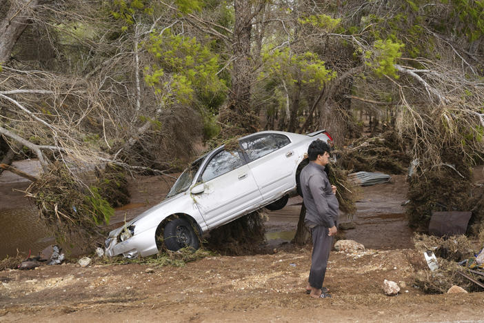In this photo provided by the Libyan government, a car sits partly suspended in trees after being carried by floodwaters in Derna, Libya, on Monday, Sept. 11, 2023.
