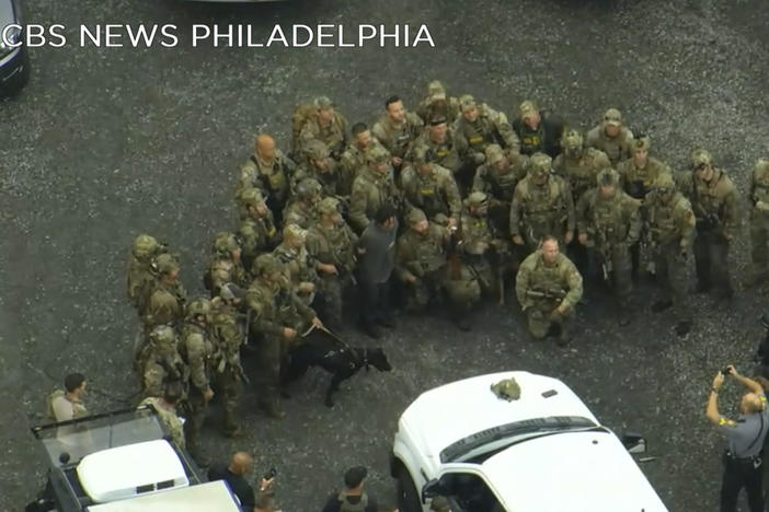 In this image from video provided by CBS NEWS Philadelphia, law enforcement officers pose for a group photo with Danelo Cavalcante after his capture in rural Pennsylvania on Wednesday, Sept. 13, 2023.