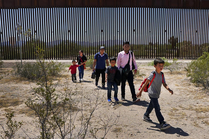 A family of five who said they were from Guatemala and a man in a pink shirt from Peru walk through the desert after crossing in the Tucson Sector of the U.S.-Mexico border last month.
