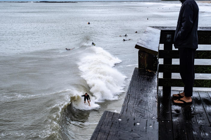 Surfers ride the waves Saturday as the ocean is whipped up by Tropical Storm Ophelia at Wrightsville Beach near Wilmington, N.C. The cyclone weakened to a tropical depression by evening.