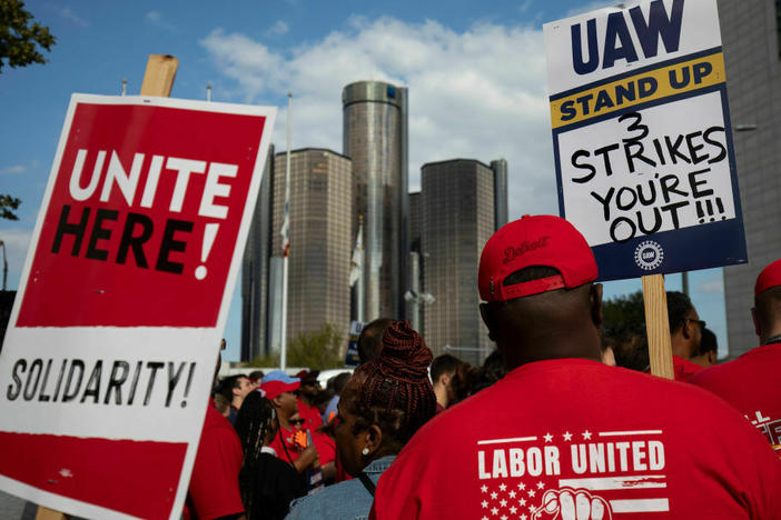 With the General Motors world headquarters in the background, United Auto Workers members attend a solidarity rally as the UAW strikes the Big Three automakers on Sept. 15 in Detroit. President Biden will join the workers in solidarity on Tuesday.