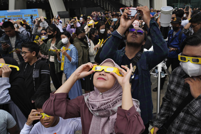 People use protective glasses to watch solar eclipse in Jakarta, Indonesia, Thursday, April 20, 2023.