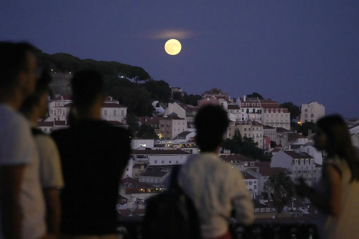People watch a supermoon rise above Lisbon, Portugal, on Aug. 30.
