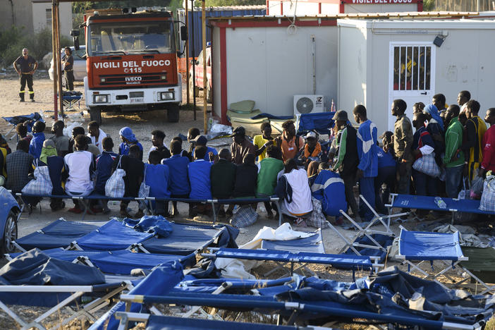 Migrants are seen standing in Lampedusa's migrant reception center on Sept. 14. The reception center in Italy's southernmost island of Lampedusa has been overwhelmed in recent weeks with transferring to the mainland thousands of migrants arriving on small, flimsy boats.