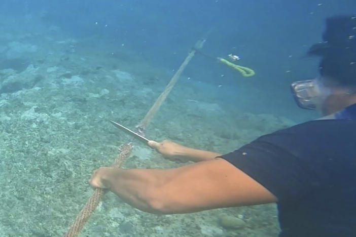 This photo, provided by the Philippine Coast Guard on Sept. 26th, shows a diver cutting rope tied to a floating barrier at the Scarborough Shoal in the South China Sea.