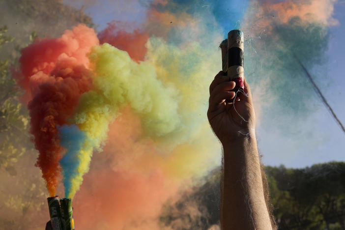 Lebanese-Armenian protesters hold flares with the colors of the Armenian flag near the Azerbaijani Embassy in Ain Aar, east of Beirut, Lebanon, Thursday, Sept. 28, 2023.