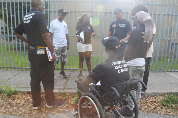 Peacemakers have a debrief before concluding their work for the day at the Lincoln Fields apartments complex in Miami, Fla. Lamont Nanton (second from left) is the group's manager and Shameka Pierce (third from left) works with the group.