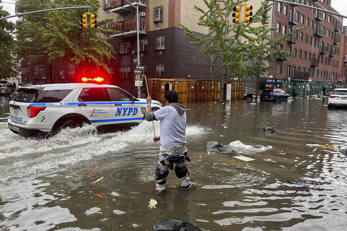 A man works to clear a drain in flood waters, Friday, Sept. 29, 2023, in the Brooklyn borough of New York.