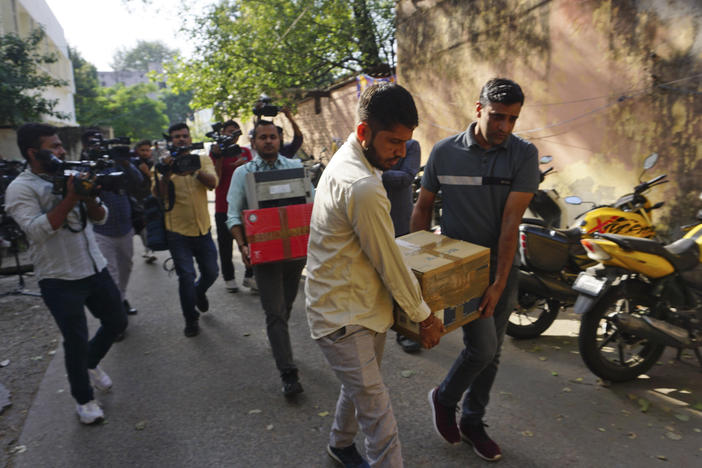 Security officers carry boxes of material confiscated after a raid at the office of NewsClick in New Delhi, India, Tuesday. Indian police raided the offices of the news website as well as the homes of several of its journalists, in what critics described as an attack on one of India's few remaining independent news outlets.