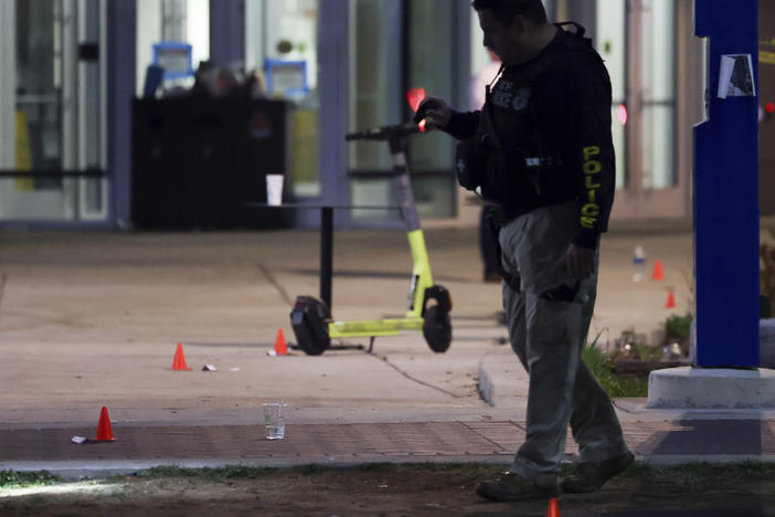 A police officer searches for evidence in front of a building at Morgan State University after a shooting, Wednesday, Oct. 4, 2023, in Baltimore.