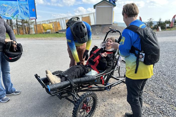 Before heading out on the trail, Carol Woody and volunteer Erwin Berry make sure Gage Tatar is safely buckled into the Cimgo. Grinning wide, Tatar listens as Woody explains what he can expect on the dirt track.