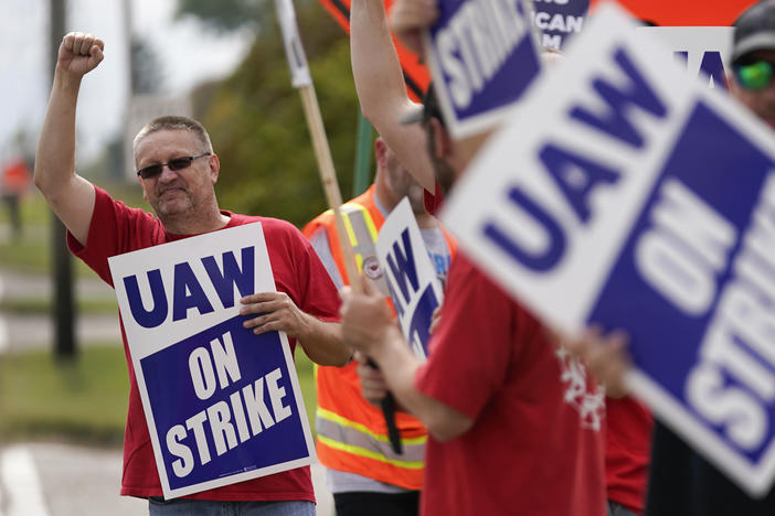 UAW members hold picket signs near a General Motors Assembly Plant in Delta Township, Mich., on Sept. 29, 2023. The UAW is gradually tightening the screws on the Big Three automakers as it pursues new contracts.