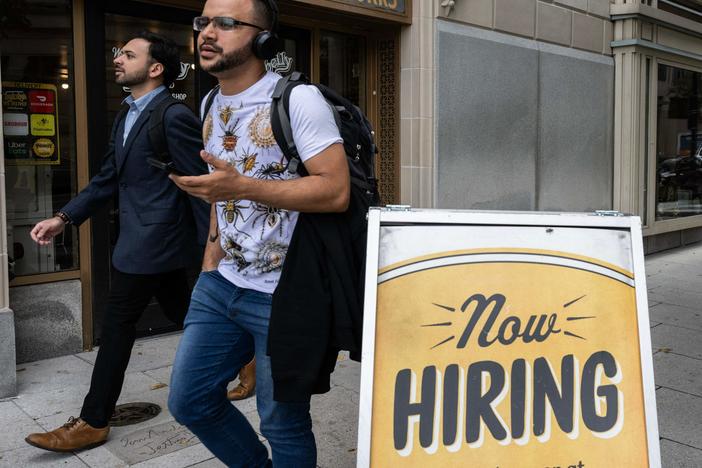 People walk past a restaurant, with a hiring sign outside in Washington, D.C., on Oct. 5, 2023. Employers added 336,000 jobs in September, far more than what analysts had predicted.